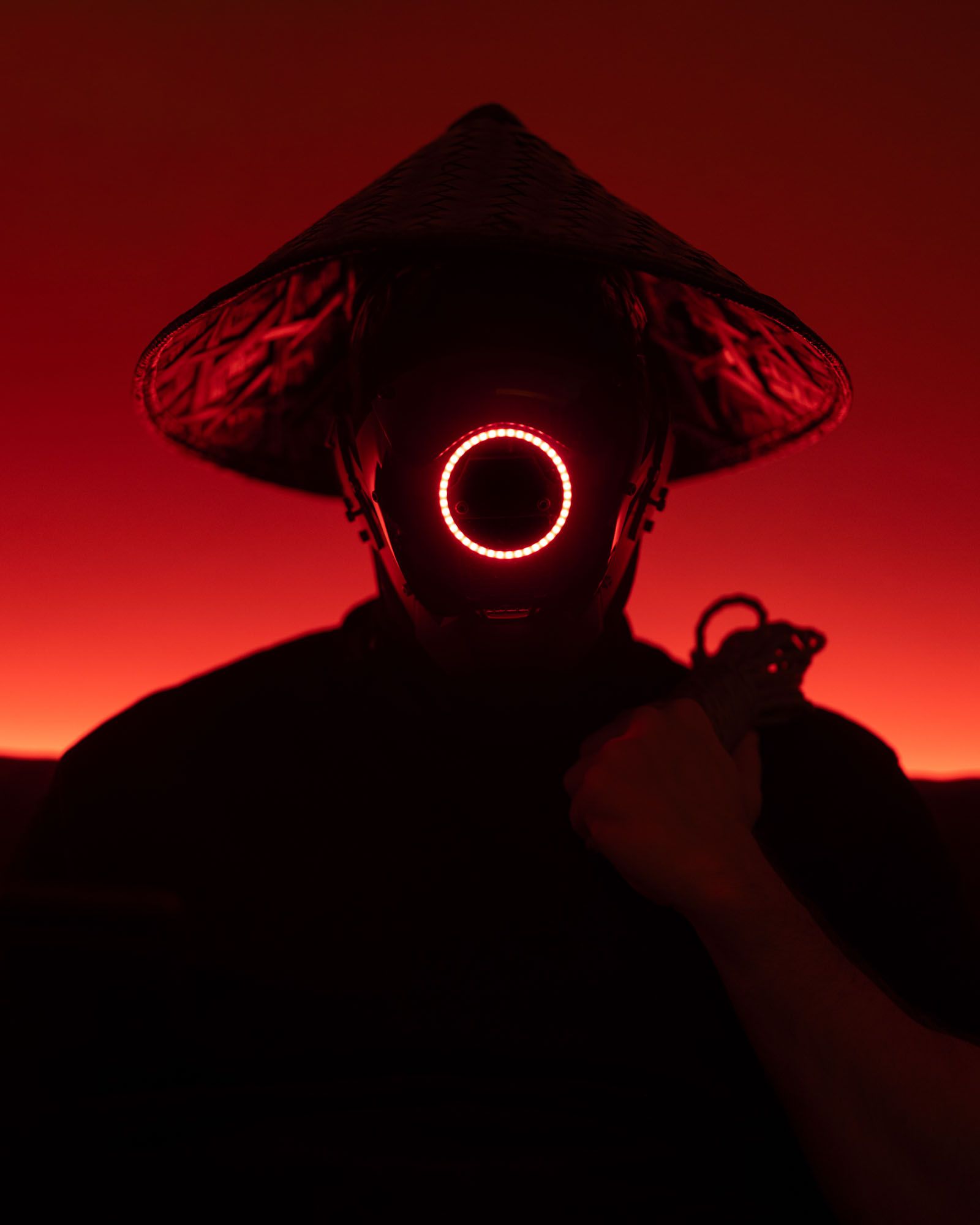 Pussynawa — figure in a conical hat and glowing LED mask, holding rope